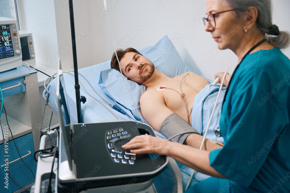 Obraz premium Experienced female specialist diagnostician makes a cardiogram to young patient