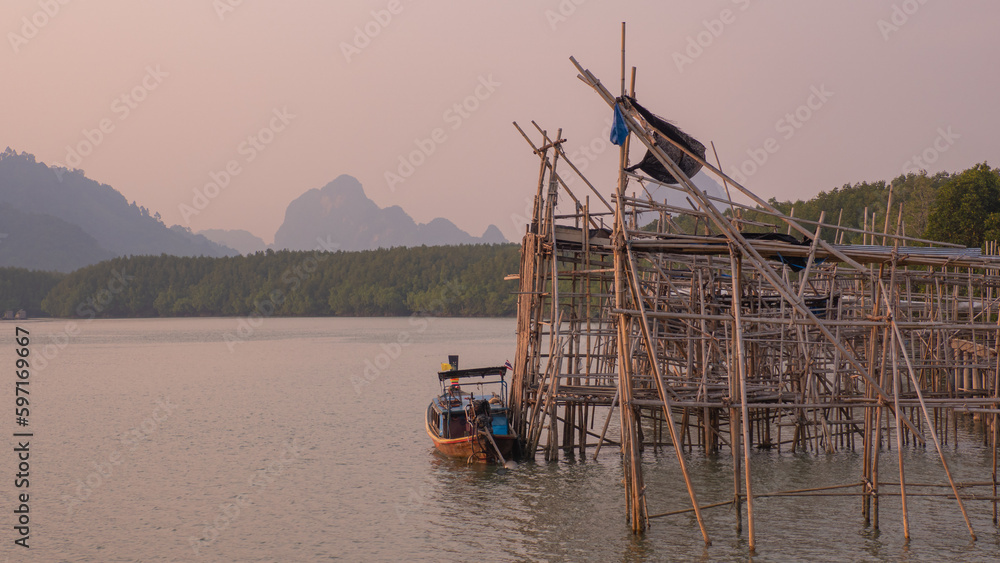 Fototapeta premium seaside port Fishermen use it to rest their boats in their ways. in a beautiful quiet setting Blue-green water and fresh green mangrove trees There is an indigo mountain backdrop.