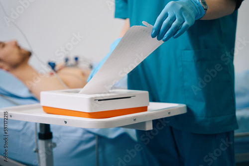Cardiologist in protective gloves takes a cardiogram to a patient
