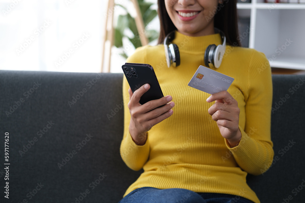 Fototapeta premium Happy optimistic young girl student holding credit card while shopping online.