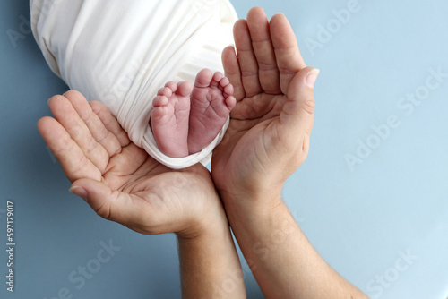 Tiny foot of a newborn baby. Soft legs of a newborn in a white blanket. Close up the toes  heels and feet of a newborn baby. Studio macro photography baby feet on a white background.