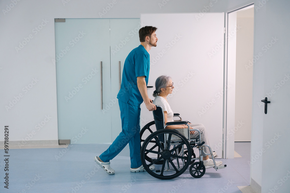 Young health worker accompanies an elderly patient in a wheelchair Young health worker accompanies an elderly patient in a wheelchair