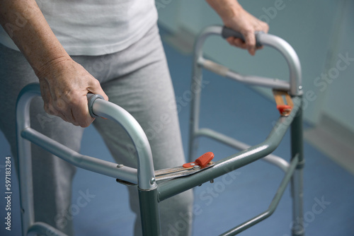Elderly patient moves with a walker along the hospital corridor