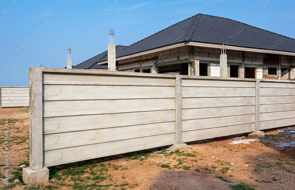Fototapeta premium Install a new fence on the construction site with the unfinished house.