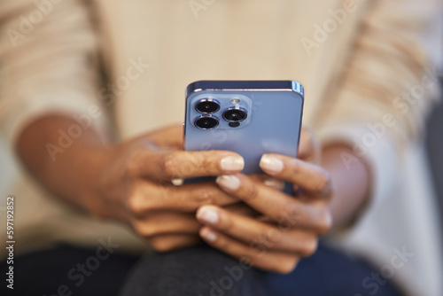 Young black woman typing text message on a smart phone. Unrecognizable BIPOC female texting online with a blue mobile phone