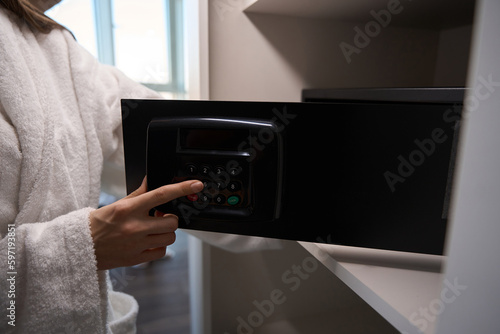 Female in a comfortable terry bathrobe opens a portable safe