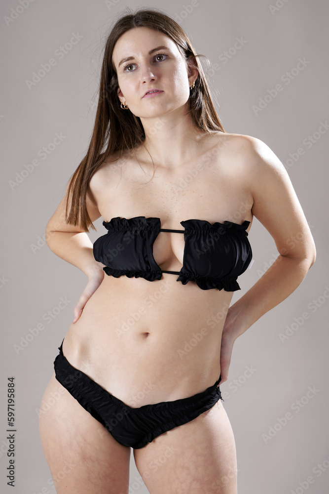 Fototapeta premium Beautiful sporty woman posing in strapless black bikini in studio