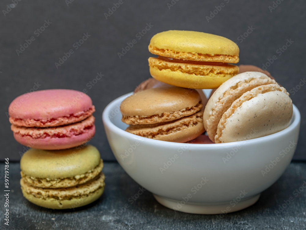 Colorful macarons in a white bowl next to a stack of two