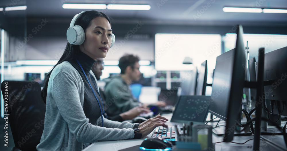 Portrait of a Thoughtful Young Engineer Working on Computer in a Technological Office Environment. Beautiful Asian Woman Wearing Headphones, Writing Software Code for a Blockchain Project Portrait of a Thoughtful Young Engineer Working on Computer in a Technological Office Environment. Beautiful Asian Woman Wearing Headphones, Writing Software Code for a Blockchain Project