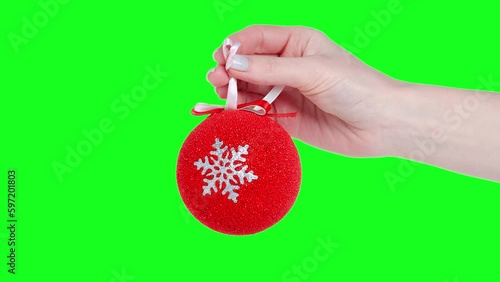Red christmas tree toy in hand isolation, green screen background