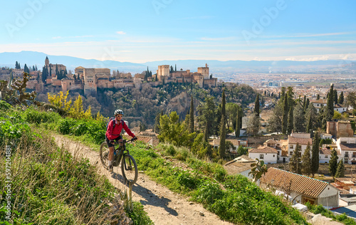 nice active senior woman cycling with her electric mountain bike in Granada below the world heritage site of Alhambra, Granada, Andalusia,  Spain photo