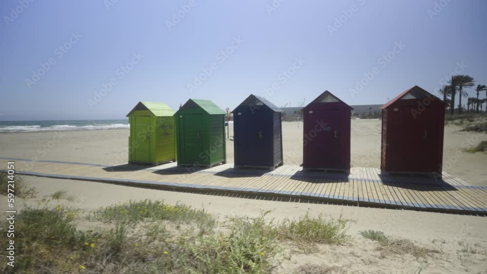 The wind on the seashore in Spain in spring. Bright colourful beach houses on the sandy beach. Castellon The wind on the seashore in Spain in spring. Bright colourful beach houses on the sandy beach. Castellon