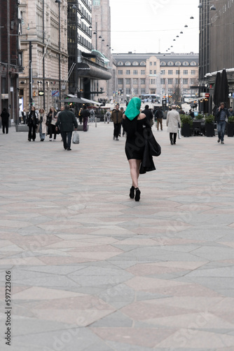 Helsinki. Finland. 25.04,2023. A woman with a perfect figure and red lips in a short black dress, a bright scarf on her head. Posing in the city