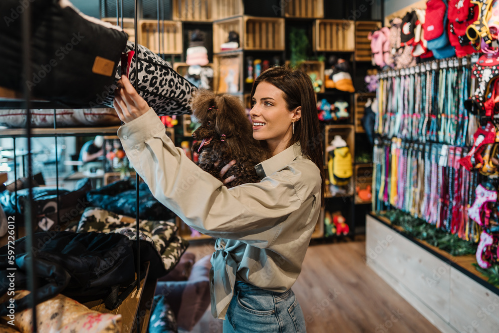 Beautiful young woman enjoying in modern pet shop together with her adorable brown toy poodle. Beautiful young woman enjoying in modern pet shop together with her adorable brown toy poodle.