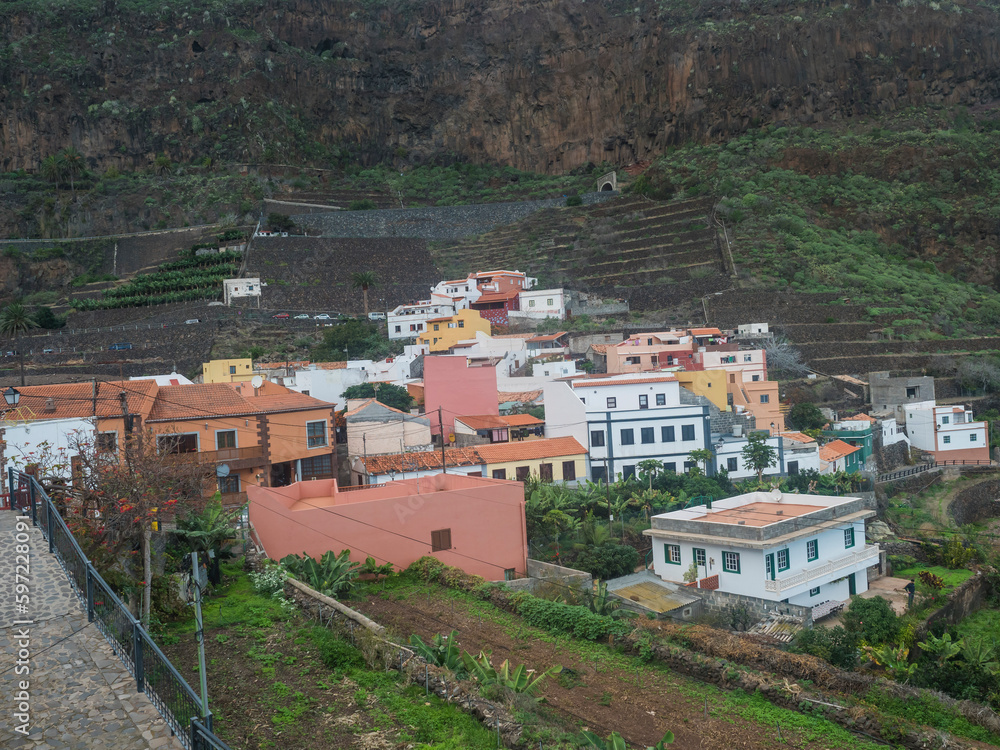 View of old village Agulo with colorful traditional houses, terraced fields and mountain in green valley at north coast. Cloudy winter day. La Gomera, Canary Islands, Spain