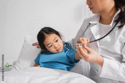 little asian child touching stethoscope near pediatrician in hospital ward. © LIGHTFIELD STUDIOS