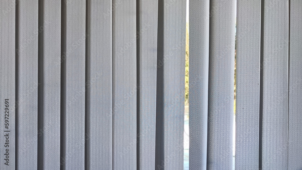 Vertical fabric white blinds on the window with the sun. Background and texture. Abstract pattern and frame. Stripes and lines of white-gray color Vertical fabric white blinds on the window with the sun. Background and texture. Abstract pattern and frame. Stripes and lines of white-gray color