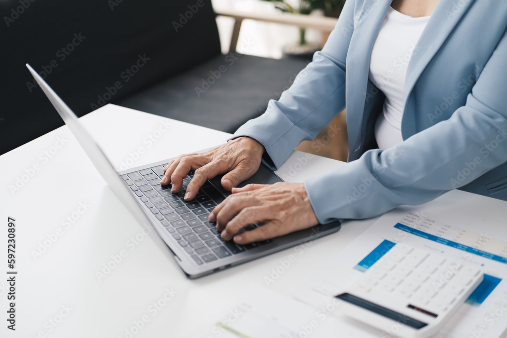 Close up view of old businesswoam working with laptop computer in the office room.