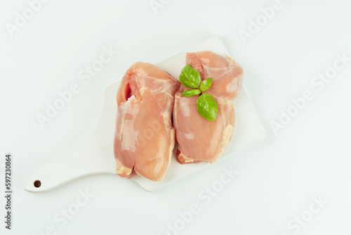 Raw fresh skinless chicken thigh meat with fresh herbs on a white background.Copy space.Food for retail.Ogranic food,healthy eating.Food concept.Top view.