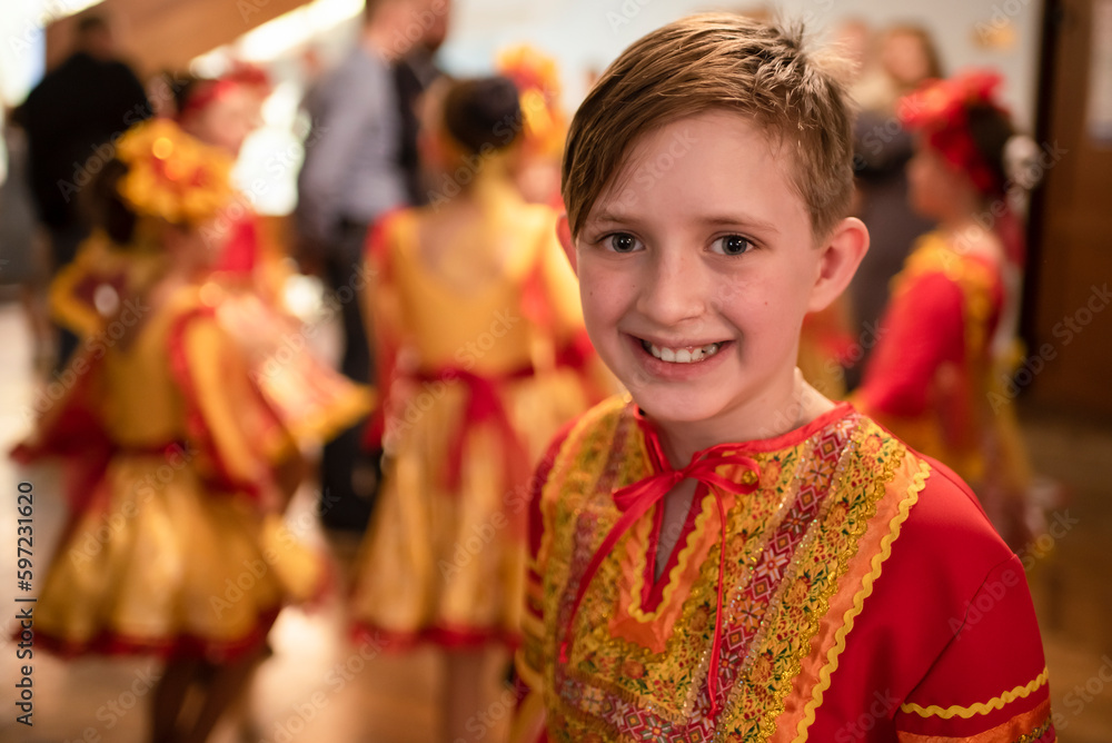 a boy dancer with his group in red-orange folk costumes are rehearsing the dance and waiting for their appearance on the stage a boy dancer with his group in red-orange folk costumes are rehearsing the dance and waiting for their appearance on the stage