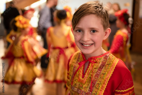 a boy dancer with his group in red-orange folk costumes are rehearsing the dance and waiting for their appearance on the stage