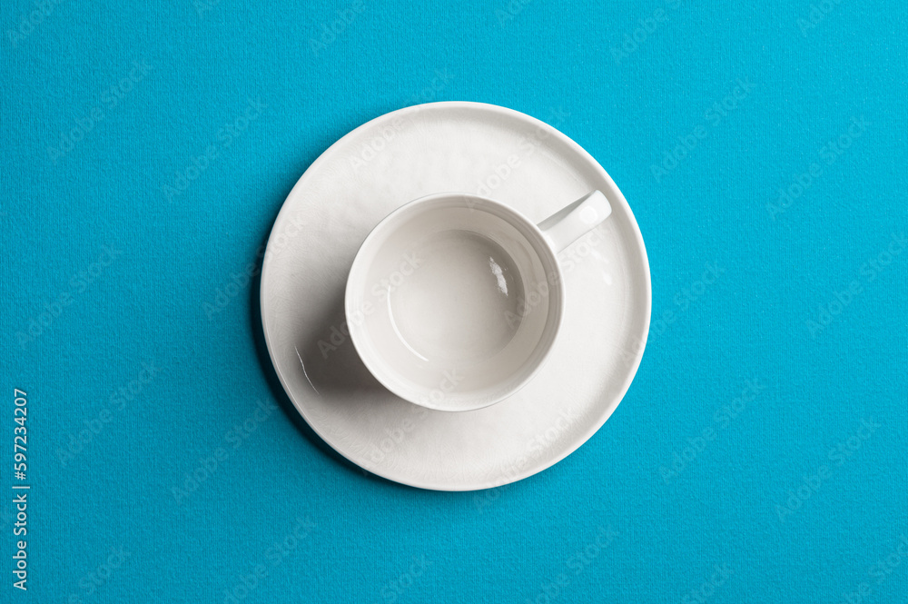 White empty cup with a saucer on a colored background. Top view. White empty cup with a saucer on a colored background. Top view.