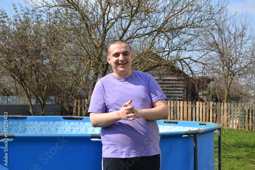 A young autistic guy is having fun walking in the garden near the pool