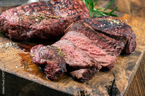 Barbecue dry aged entrecote beef steak sliced and served as close-up on a rustic wooden board