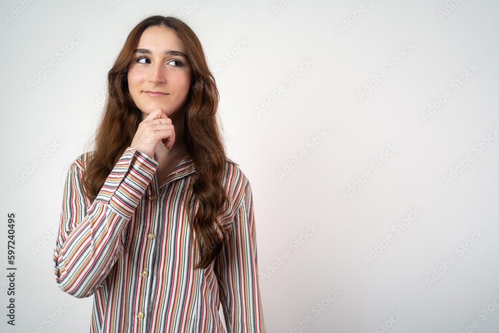 Pensive smiling teenager girl isolated on grey studio background look at copy space aside. Pensive smiling teenager girl isolated on grey studio background look at copy space aside.