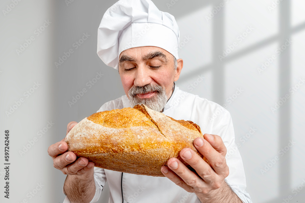 Professional baker quality checker smell the scent freshly baked bread. Chef-cooker in a chef's hat and jacket. Senior baker man wearing a chef's outfit. Character kitchener, pastry chef Professional baker quality checker smell the scent freshly baked bread. Chef-cooker in a chef's hat and jacket. Senior baker man wearing a chef's outfit. Character kitchener, pastry chef