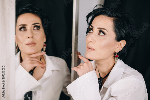 Obraz na płótnie Radiant woman with brilliant eyes in white shirt posing with a mirror and examining her reflection w salonie