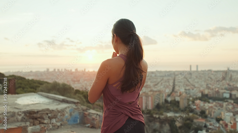 Girl meditates sitting on the observation deck at dawn, Back view