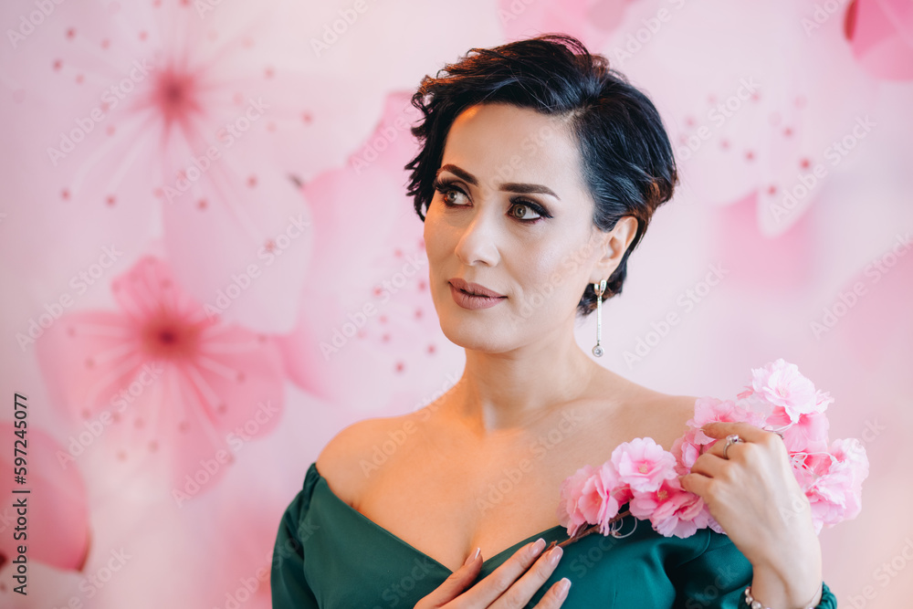 A closeup of cute woman holding artifical pink flowers in front of pink background