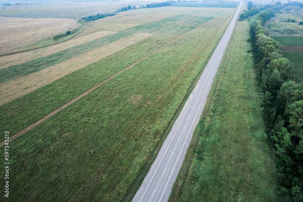 the road going into the distance across the field, the view from the drone