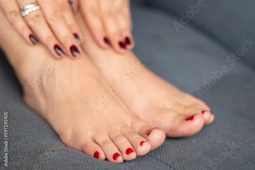 Stylish pedicure on a Latina woman's feet while she lounges on a sofa