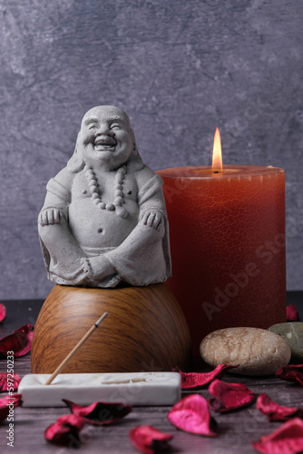 Close-up Buddha statue with candles, stones and incense, meditation and relaxation, vertical