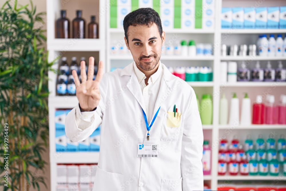 Handsome hispanic man working at pharmacy drugstore showing and pointing up with fingers number four while smiling confident and happy. Handsome hispanic man working at pharmacy drugstore showing and pointing up with fingers number four while smiling confident and happy.