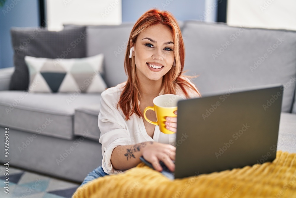 Young caucasian woman using laptop and earphones drinking coffee at home Young caucasian woman using laptop and earphones drinking coffee at home