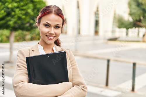 Young caucasian woman business worker holding binder at street © Krakenimages.com