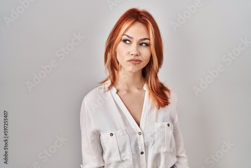 Young caucasian woman standing over isolated background smiling looking to the side and staring away thinking.