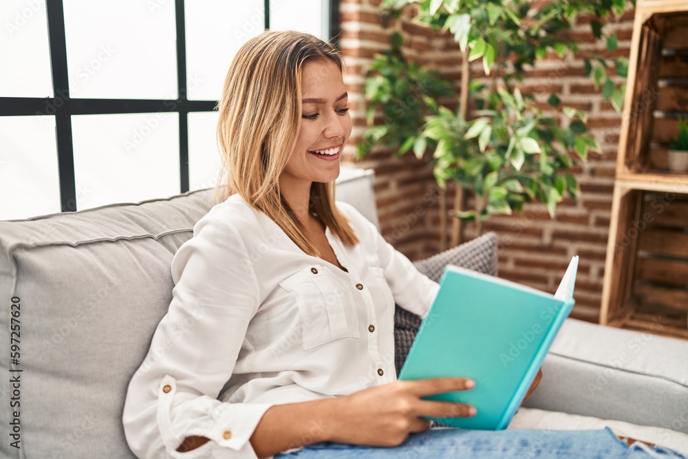 Young hispanic woman reading book sitting on sofa at home Young hispanic woman reading book sitting on sofa at home