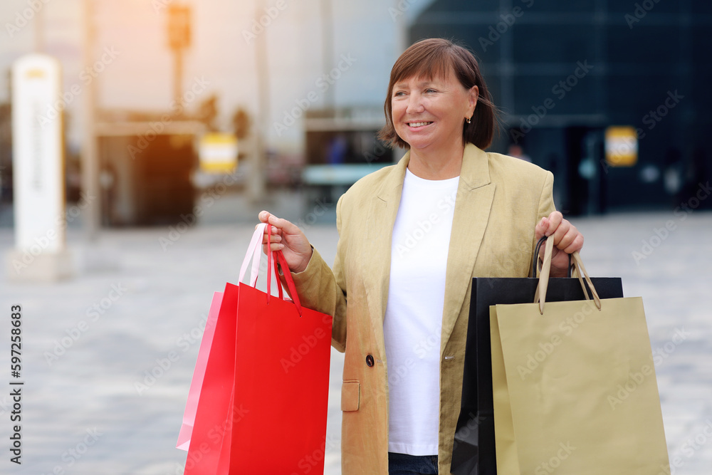 Seasonal Sales. Happy adult woman with shopping bags. Middle ages female after shopping on shopping mall background. Purchases, discounts, sale concept. Online shopping concept, Black friday. mockup