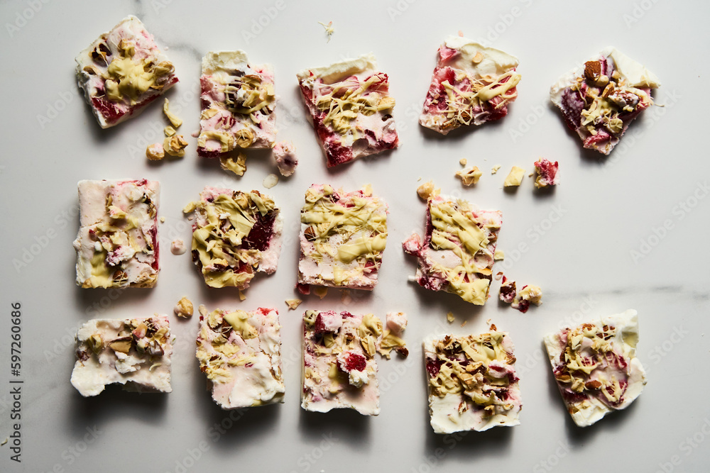 Healthy Frozen Greek Yogurt bars with strawberry with lime zest, nuts and white chocolate. Homemade sweet dessert on white marble background. Top view, bright high key food photo Healthy Frozen Greek Yogurt bars with strawberry with lime zest, nuts and white chocolate. Homemade sweet dessert on white marble background. Top view, bright high key food photo