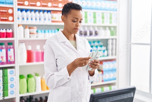 African american woman pharmacist counting dollars at pharmacy photo