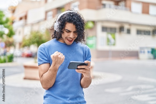 Young latin man smiling confident playing video game at street