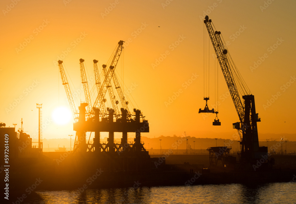 Fototapeta premium Cranes in the port with beautiful sunset in the background