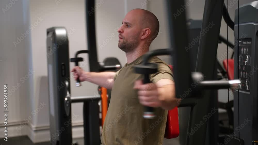 Athlete bodybuilder pumping muscles in the gym, flattens the chest muscles in the trainer. Athlete bodybuilder pumping muscles in the gym, flattens the chest muscles in the trainer.
