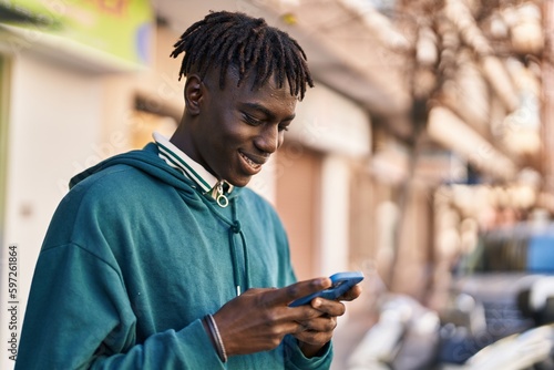 African american man smiling confident using smartphone at street