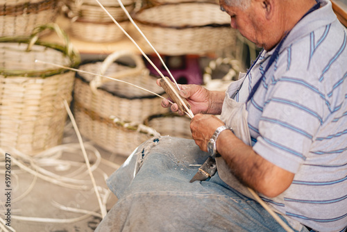 South American wicker artisan preparing sticks for weaving wicker baskets at his workshop