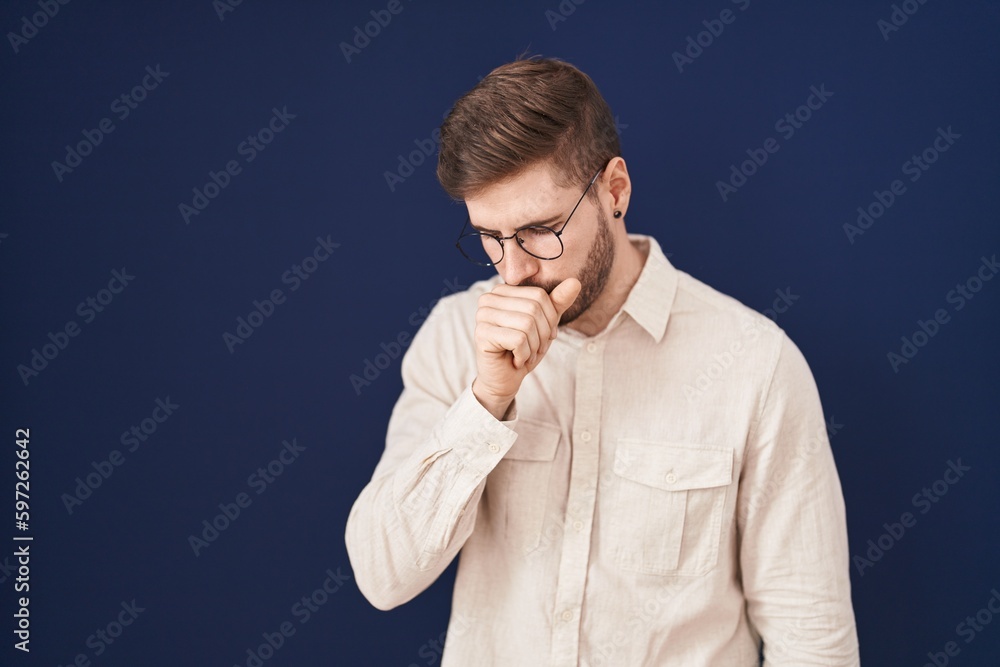 Hispanic man with beard standing over blue background feeling unwell and coughing as symptom for cold or bronchitis. health care concept. Hispanic man with beard standing over blue background feeling unwell and coughing as symptom for cold or bronchitis. health care concept.